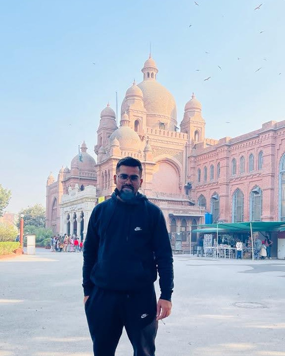 Naveed in front of a landmark building in Lahore